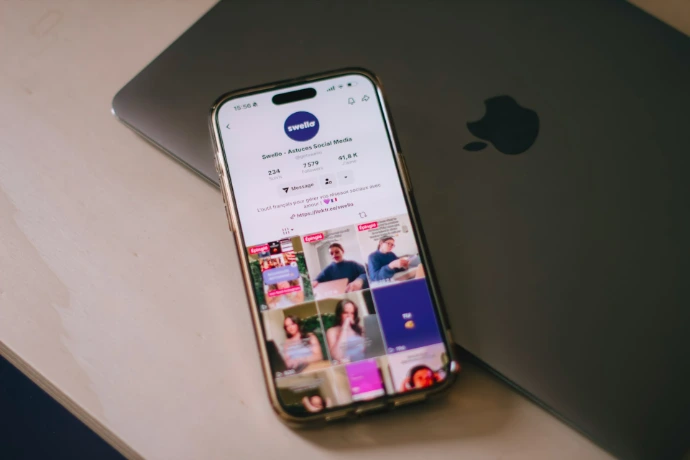 Smartphone displaying social media next to laptop